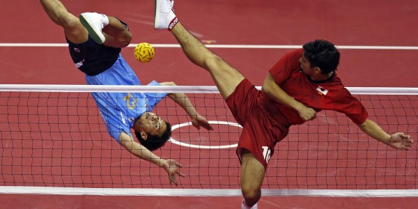 Two players playing Sepak-takraw in the stadium